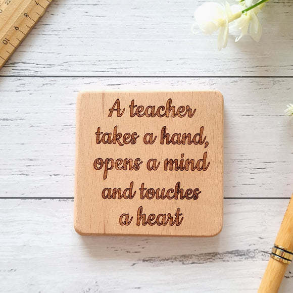 A teacher takes a hand, opens a heart and touches a heart coaster teacher gift